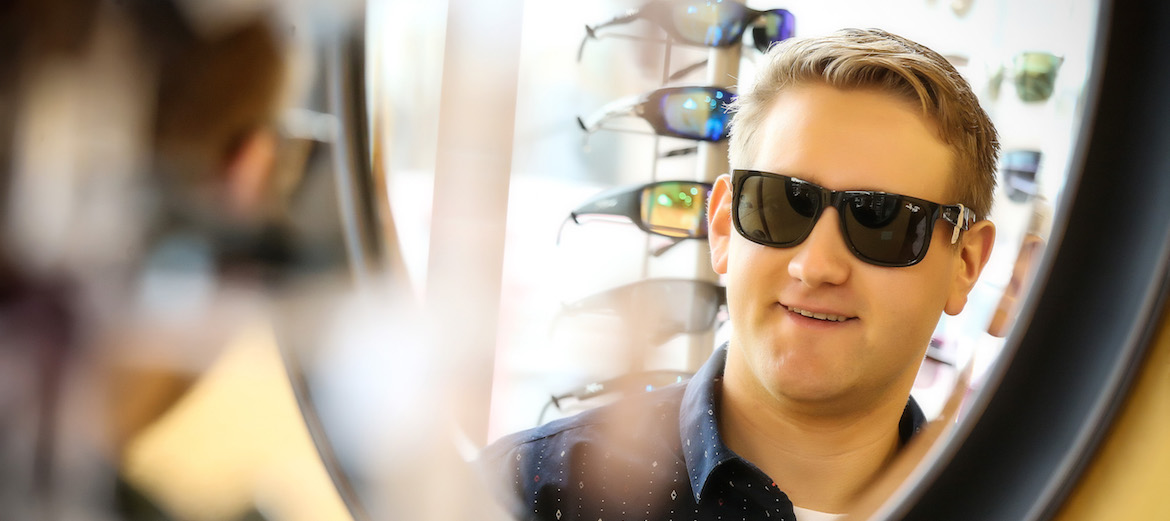 man trying on sunglasses and smiling